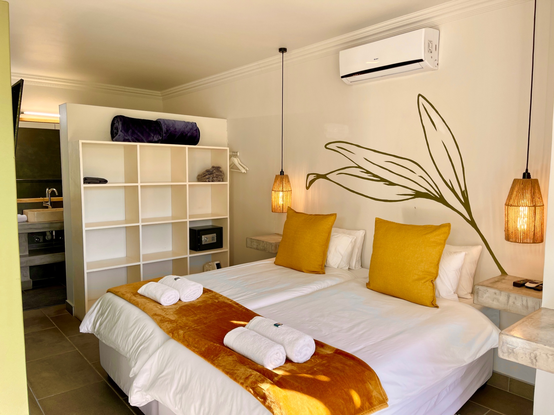 Twin beds with mustard cushions and olive leaf mural
